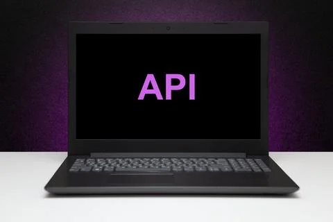 API text on laptop screen on textured black background with purple light. Stockfoto's