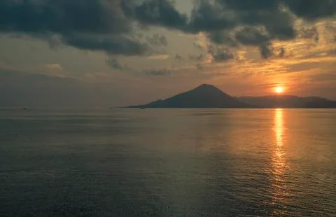 Api volcano mountain and sunset or sunrise with long sunbeam over the banda sea Foto stock