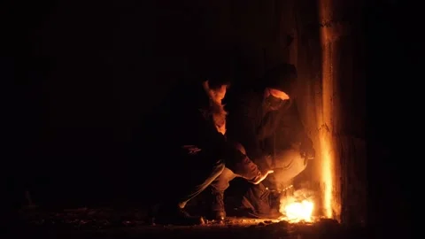 Apocalyptic footage of two young poor homeless guys heating their hand on fire Stock Footage 144670229