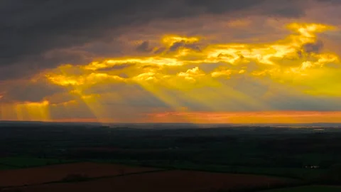 Apocalyptic golden sun rays breaking through heavy storm clouds above dark Stock Footage 338069511