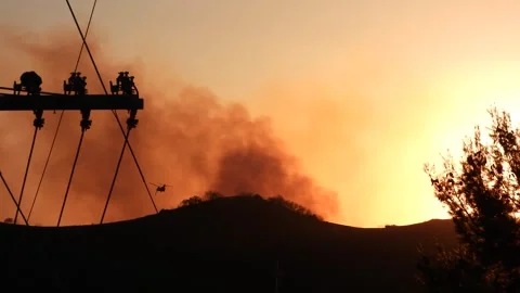 Apocalyptic smoke rises off mountains at sunset, army helicopter silhouette Stock Footage 305533628
