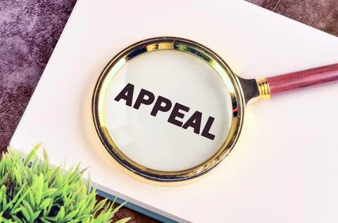 APPEAL text written in a notebook through a magnifying glass, top view. Conce Stock Photos