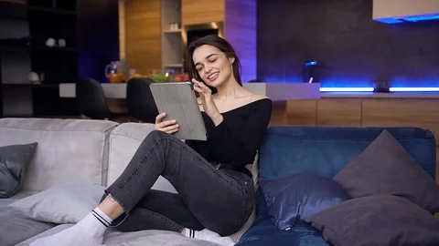Appealing joyful modern young brunette woman in black top and jeans sitting on Stock Footage 127098763