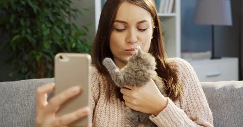 Appealing young woman making cute selfies with a pretty small kitty on the smart Stock Footage 82670870