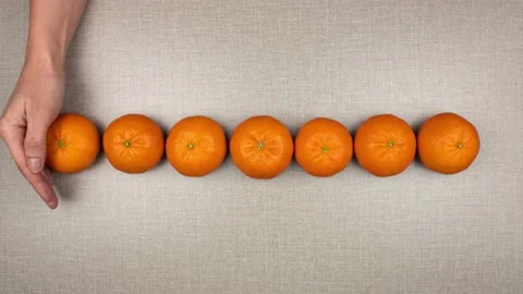 The appearance of a tangerine on the table from under a woman's hand. 스톡 동영상 150431470
