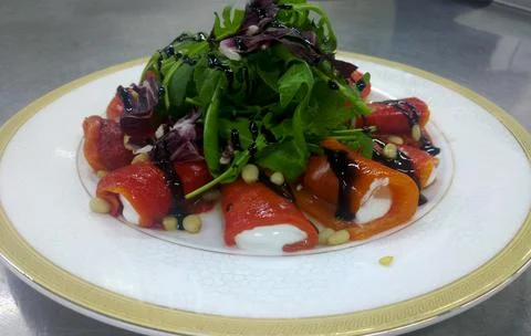 Appetizer of baked peppers with tender cream cheese with a mix of greens Stock Photos