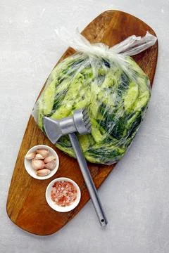 Appetizer Broken salted cucumbers in a plastic bag on a wooden cutting board Stock Photos
