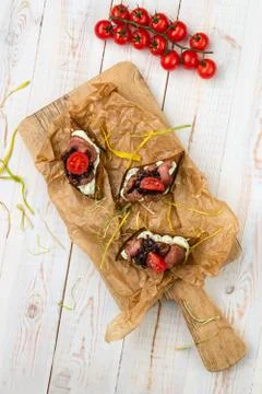 Appetizer with brown bread croutons, ham, sauce and cherry tomatoes on cuttin 스톡 사진