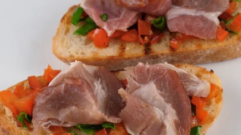 Appetizer bruschetta with prosciutto and chopped vegetables, close-up view Stock Footage 79925500