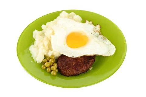 Appetizer of cutlet with fried egg, mashed potatoes and green peas, on a plat Stock Photos
