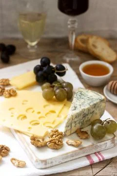 Appetizers of various types of cheese, grapes, nuts and honey, served with wh Stock Photos