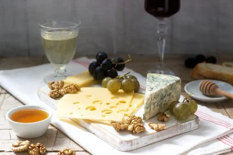 Appetizers of various types of cheese, grapes, nuts and honey, served with wh Stock Photos