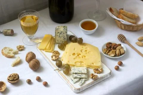 Appetizers of various types of cheese, grapes, nuts and honey, served with wh Stock Photos