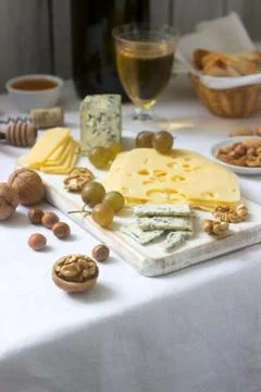 Appetizers of various types of cheese, grapes, nuts and honey, served with wh Stock Photos