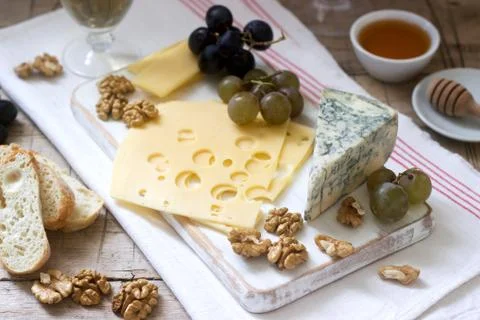 Appetizers of various types of cheese, grapes, nuts and honey, served with white Stock Photos