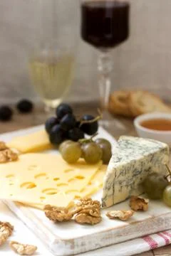 Appetizers of various types of cheese, grapes, nuts and honey, served with white Stock Photos
