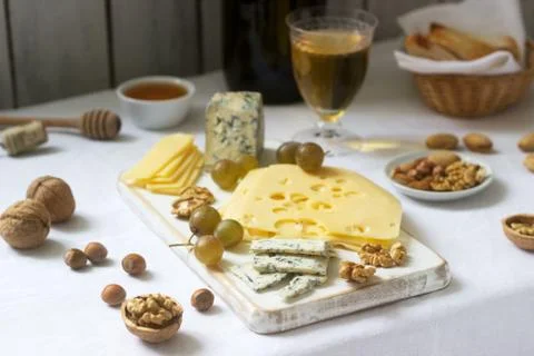 Appetizers of various types of cheese, grapes, nuts and honey, served with white Stock Photos