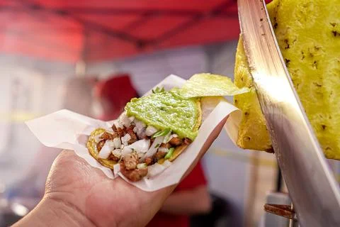 Appetizing adobada taco held by one hand Stock Photos