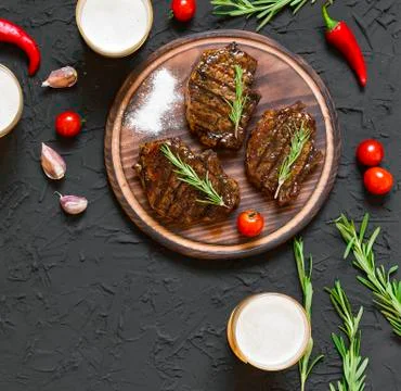 Appetizing beef steaks, beer and rosemary Photos