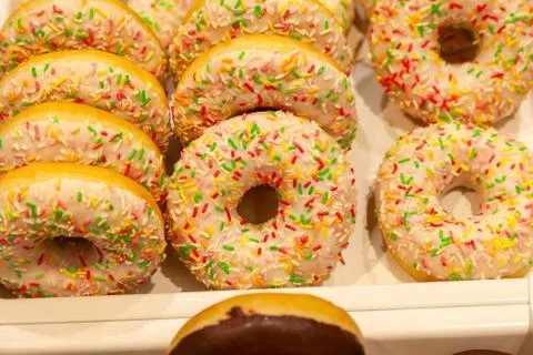 Appetizing big white donuts with white icing and multi-colored confetti, made Stock Photos