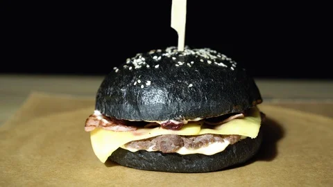 Appetizing black burger with cutlet, bacon, cheese and cherry sauce Stock Footage 113607426