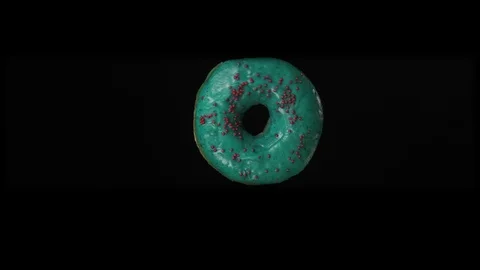 An appetizing, blue donut rotates on a black background, close-up. Stock Footage 125831968