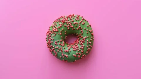 Appetizing bright fresh doughnut with green icing rotating isolated on pink. 4k Stock Footage 152762045