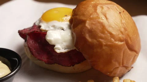 Appetizing burger with bacon, a fried egg, and french fries served on a platter Stock Footage 333531504
