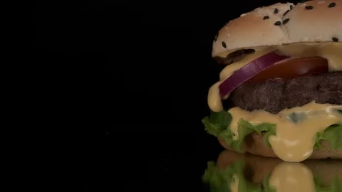 An appetizing burger with a with meat, tomato, onion and salad close-up, a fire Stock Footage 125830554