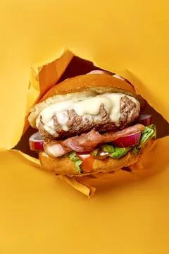 Appetizing burger with pineapple and cheese, bacon breaks through yellow back Stock Photos