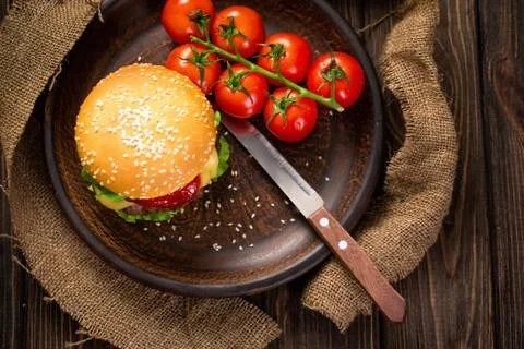 Appetizing burger with tomatoes on table Stock Photos