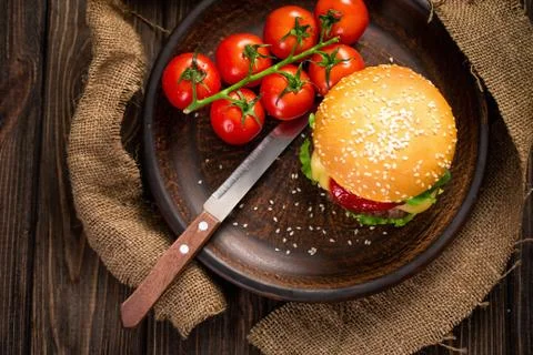 Appetizing burger with tomatoes on table Stock Photos