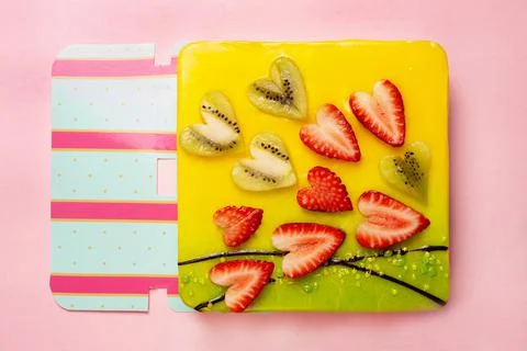 Appetizing cake covered with icing, decorated with hearts from pieces of stra Stock Photos