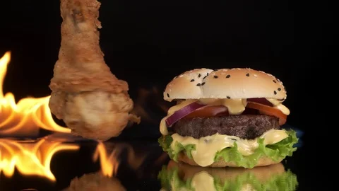 Appetizing, the chicken leg rotates next to the burger, the fire in the Video stock 125832879