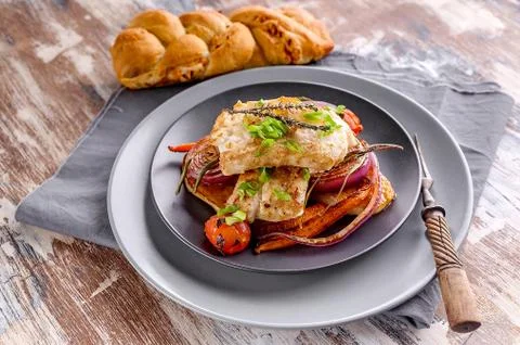 Appetizing cod filet with red onion and herbs, baked potatoes and carrots on  Stock Photos
