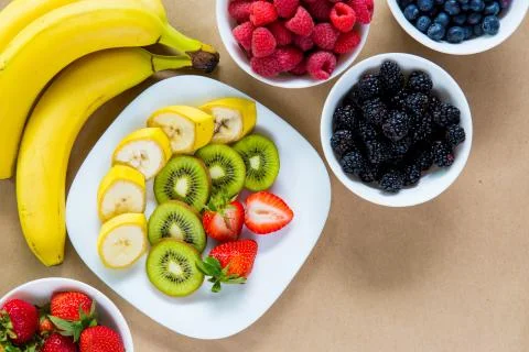 Appetizing composition of fresh bananas, strawberries, kiwis, raspberries, bl Stock Photos