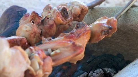 Appetizing crispy chicken is cooked at the stake. wild cooking on the beach, cam Stock Footage 137965185