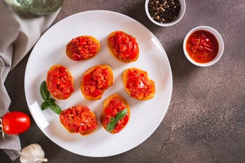 Appetizing crostini on bread with fried tomatoes and garlic on a plate top vi Stock Photos