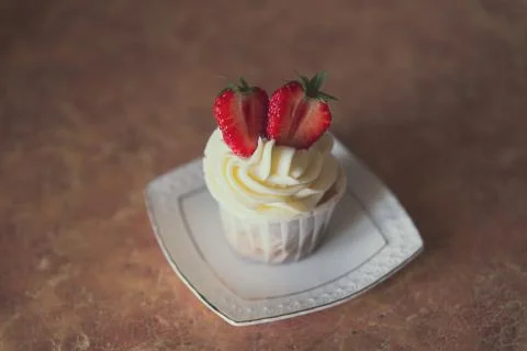 Appetizing cupcake with white cream decorated with fresh strawberries on the  Stock Photos