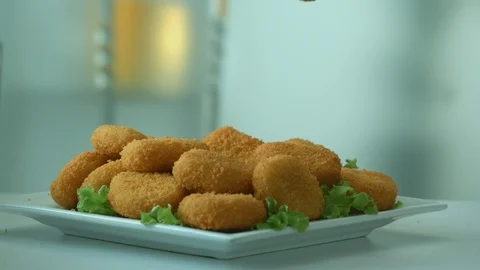 Appetizing delicious breaded chicken nuggets on falling on a plate Video stock 116877000