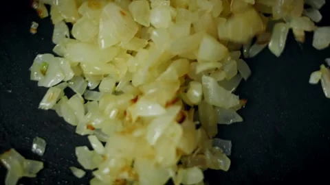 Appetizing diced onions turning translucent in a dark frying in side view, 4K Stock Footage 341110177