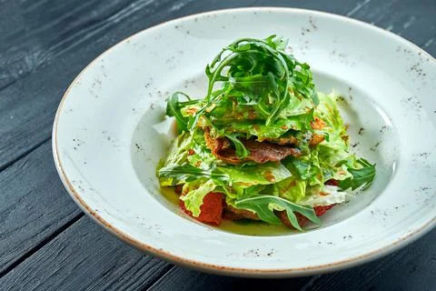 Appetizing, dietary salad with arugula, sauce, lettuce and warm beef in a whi Stock Photos