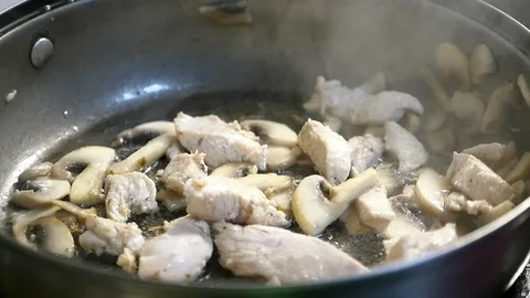 An appetizing dish from sliced meat and white mushrooms is mixed with a spatula Stock-Footage 86594373