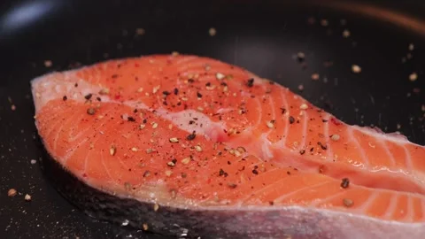 Appetizing fish steak is fried in a pan. Sprinkling grated pepper mix over Vídeos de archivo 316215291
