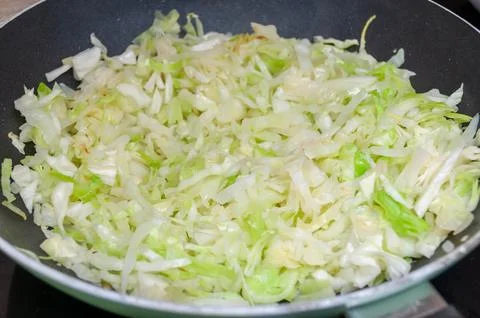 Appetizing fried cabbage in an old frying pan on an old wooden background close Stock Photos
