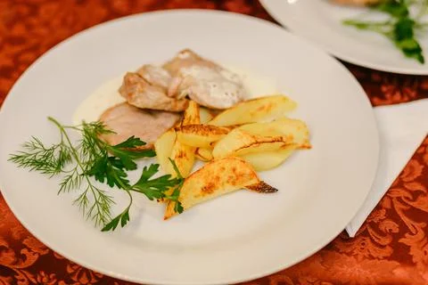 Appetizing fried potatoes with greens and pork meat on white plate Stock Photos