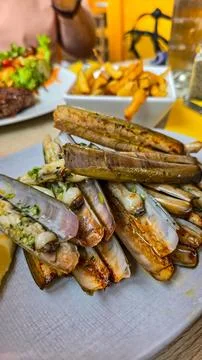 Appetizing fried shells sword razor with garlic and parsley. Nearby is fried Stock Photos