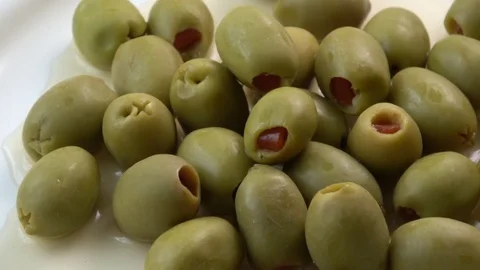 Appetizing green olives stuffed with red pepper in white plate Stock Footage 85218617