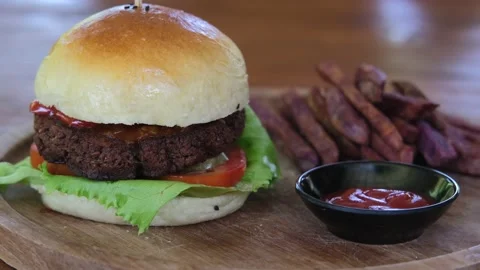 An appetizing hamburger is placed on a restaurant table on a wooden board with a Video stock 201278416