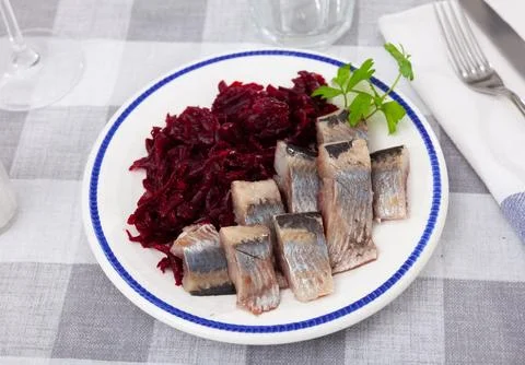 Appetizing herring salad with beets, sour cream and parsley in white plate Stock Photos